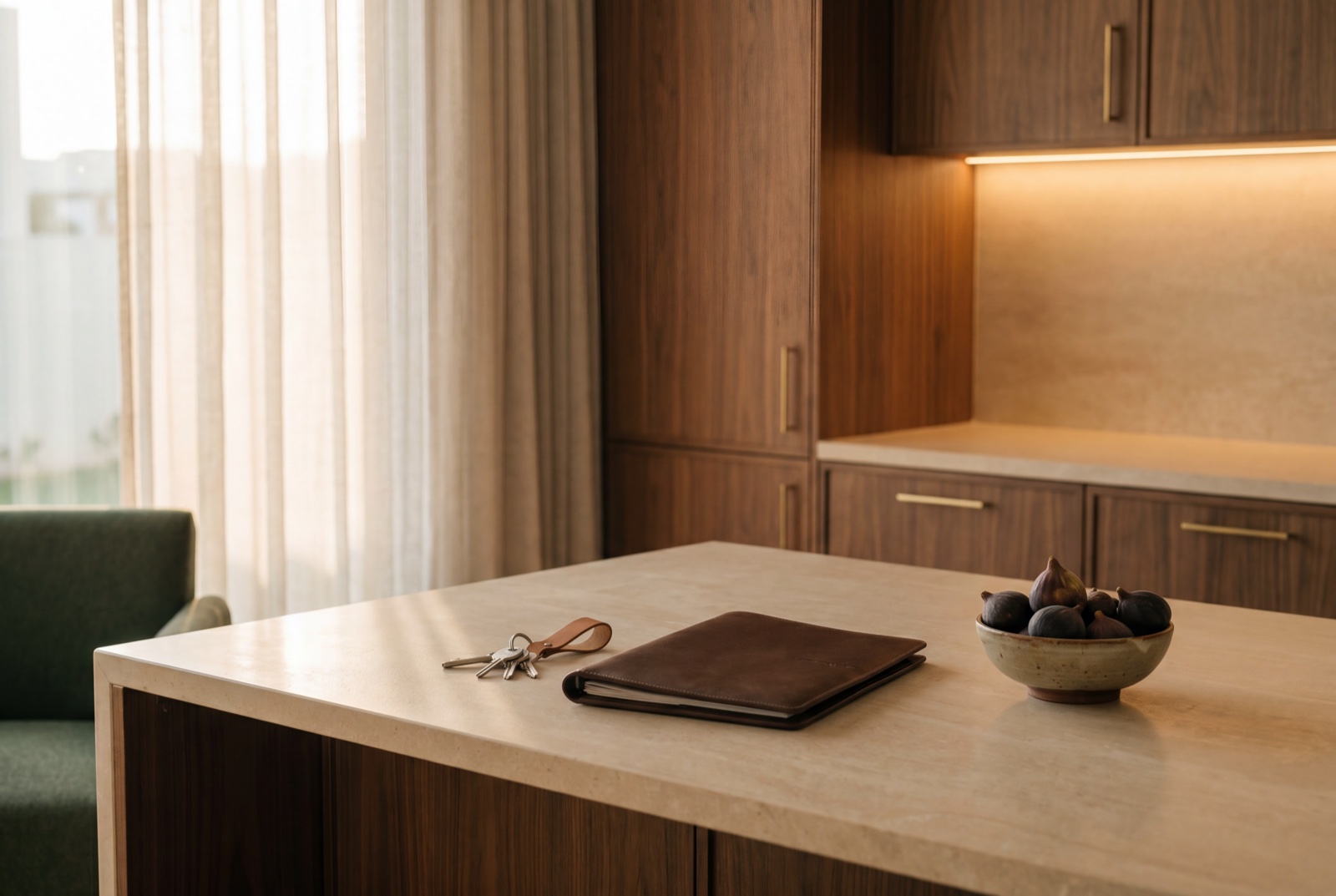 A finished kitchen at golden hour — a set of keys and a leather document folder resting on the stone island