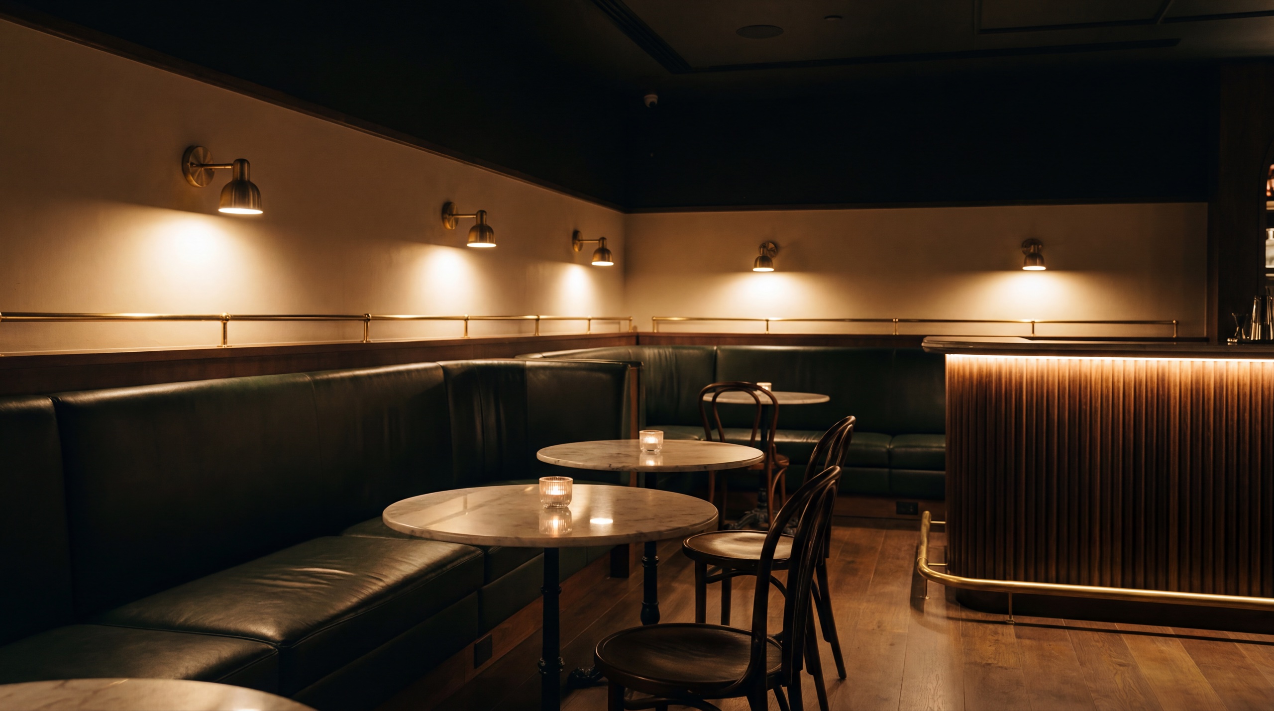 The dining room from the corner banquette – candles lit on every table, brass lamps glowing, doors still shut